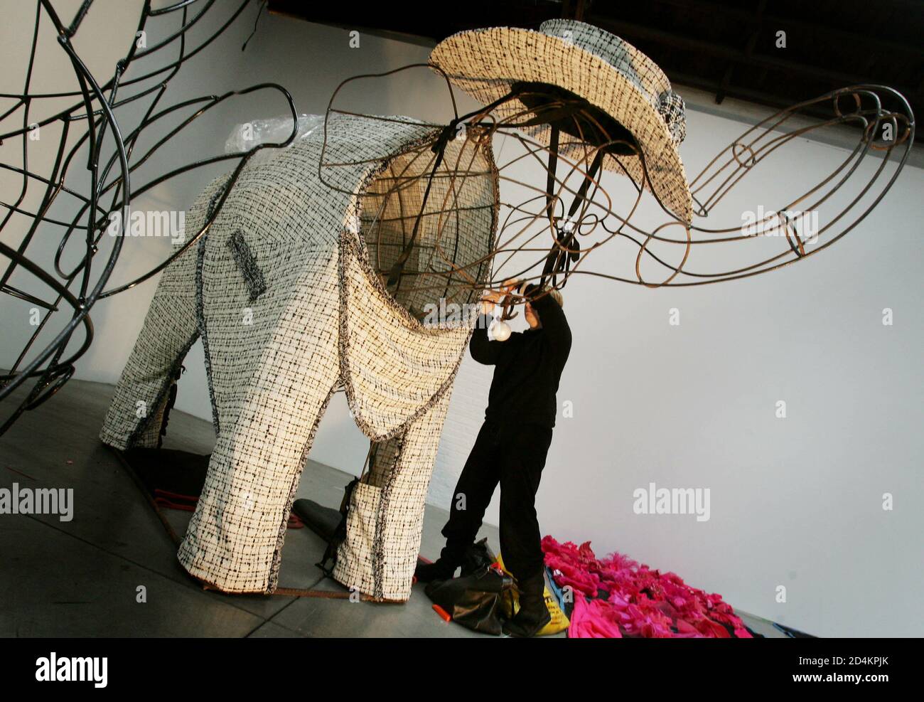 A worker dresses a giant wire elephant with a custom made outfit by  Designer Karl Lagerfeld in preparation for a W Magazine exhibition in New  York, December 7, 2004. [W Magazine asked