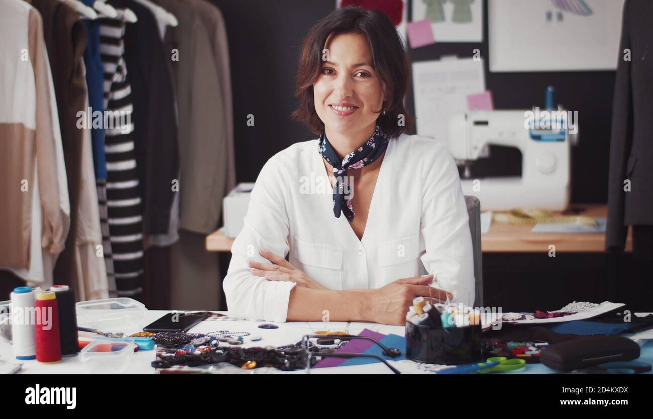 Couturière table assise sourire caméra Banque D'Images