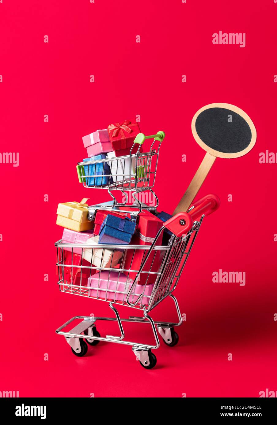 Concept d'achat de Noël avec un panier plein de cadeaux et une affiche vide pour la vente et la réduction. Panier avec cadeaux isolés sur fond rouge Banque D'Images