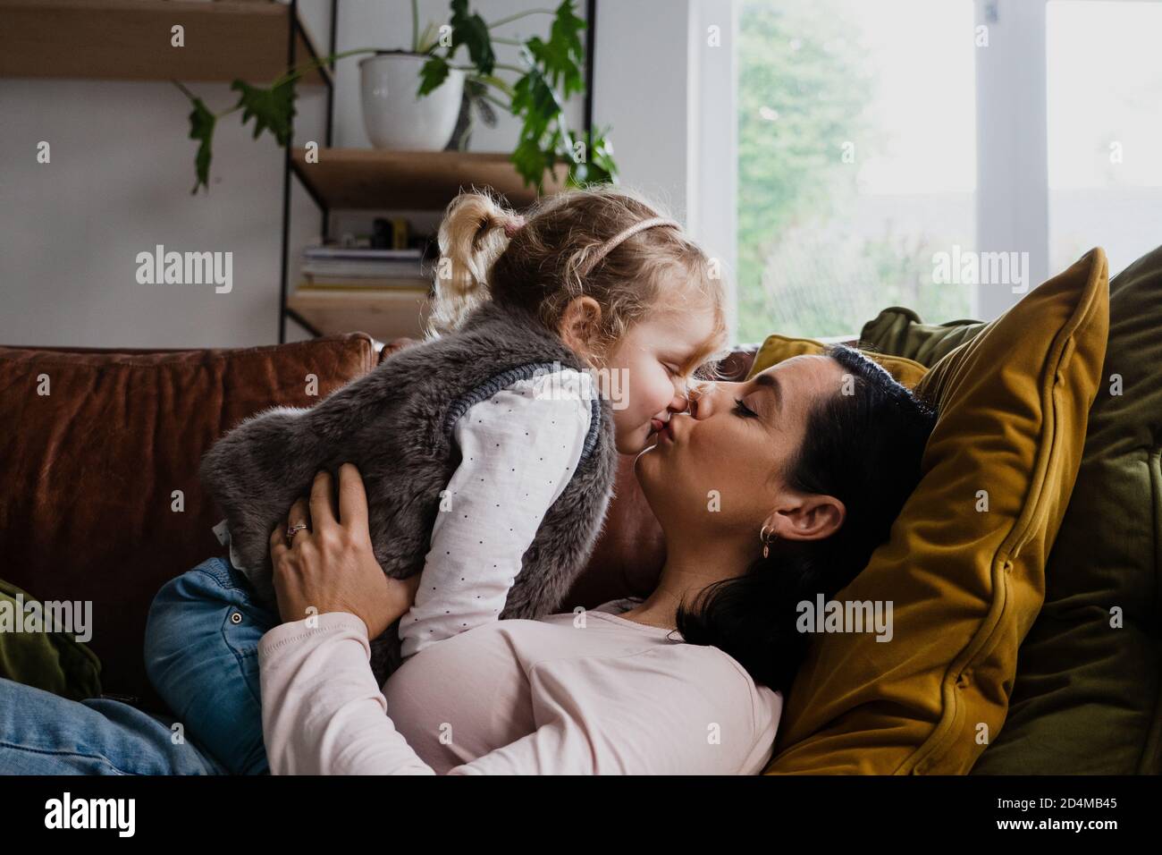 Mère et fille embrassent avec un baiser sur le canapé à la maison Photo Stock Alamy