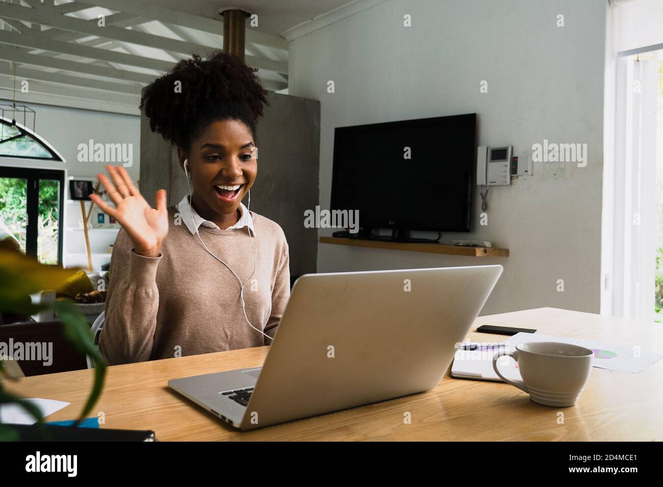 Belle femme de race mixte travaillant à domicile, lors d'un appel vidéo avec des collègues de travail Banque D'Images