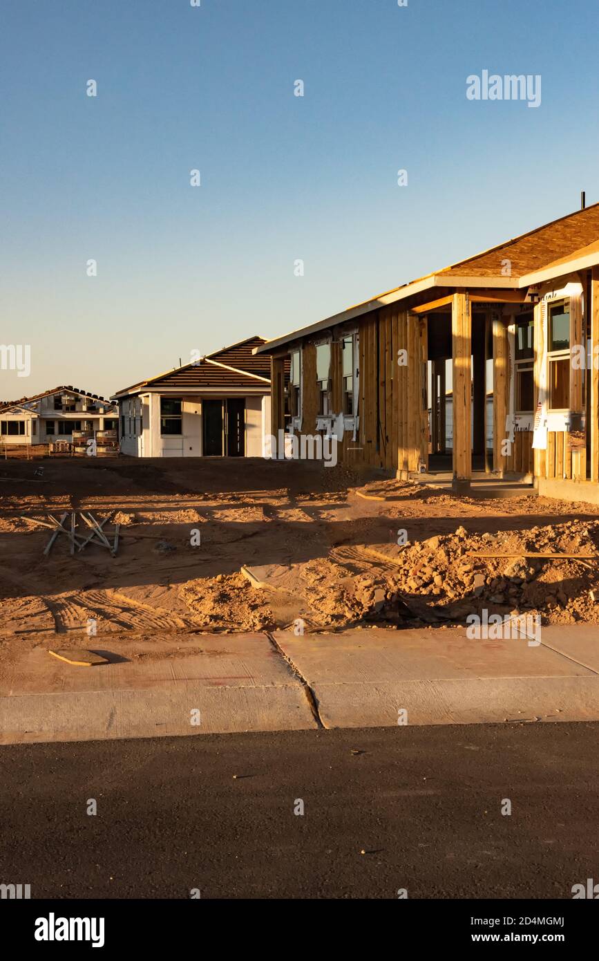 Une nouvelle construction de maison qui montre le cadre en bois se dresse parmi d'autres nouvelles maisons en début de matinée lumière dans l'Arizona bâtiment boom, vue verticale. Banque D'Images