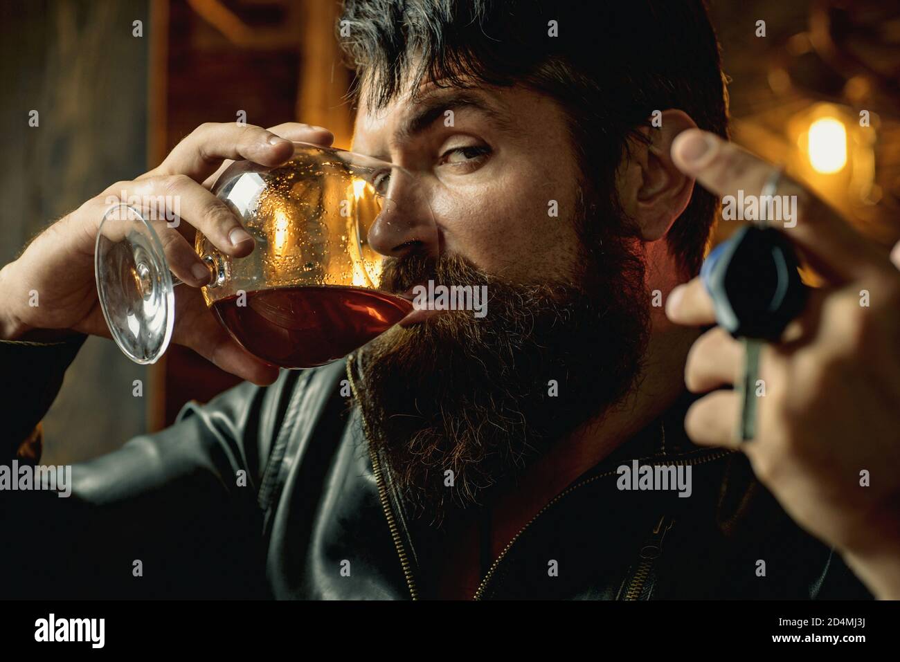 Homme avec la barbe tient le brandy de verre. Consommation de macho. Homme confiant avec des clés de voiture dans sa main. Ne conduisez pas en état d'ivresse. Arrêtez de boire. Banque D'Images