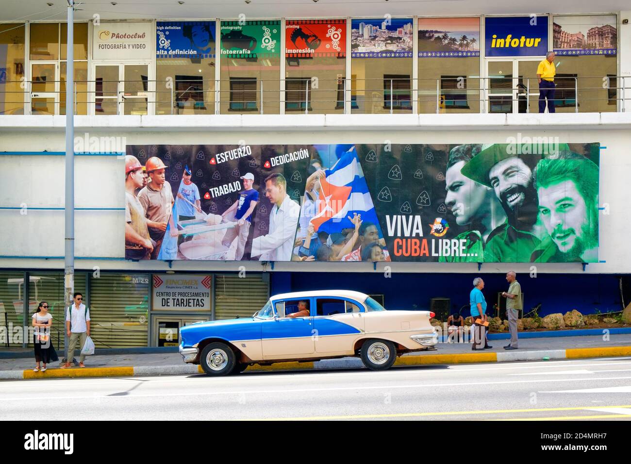 Vieille voiture classique à côté d'un panneau d'affichage avec des slogans révolutionnaires À la Havane Banque D'Images