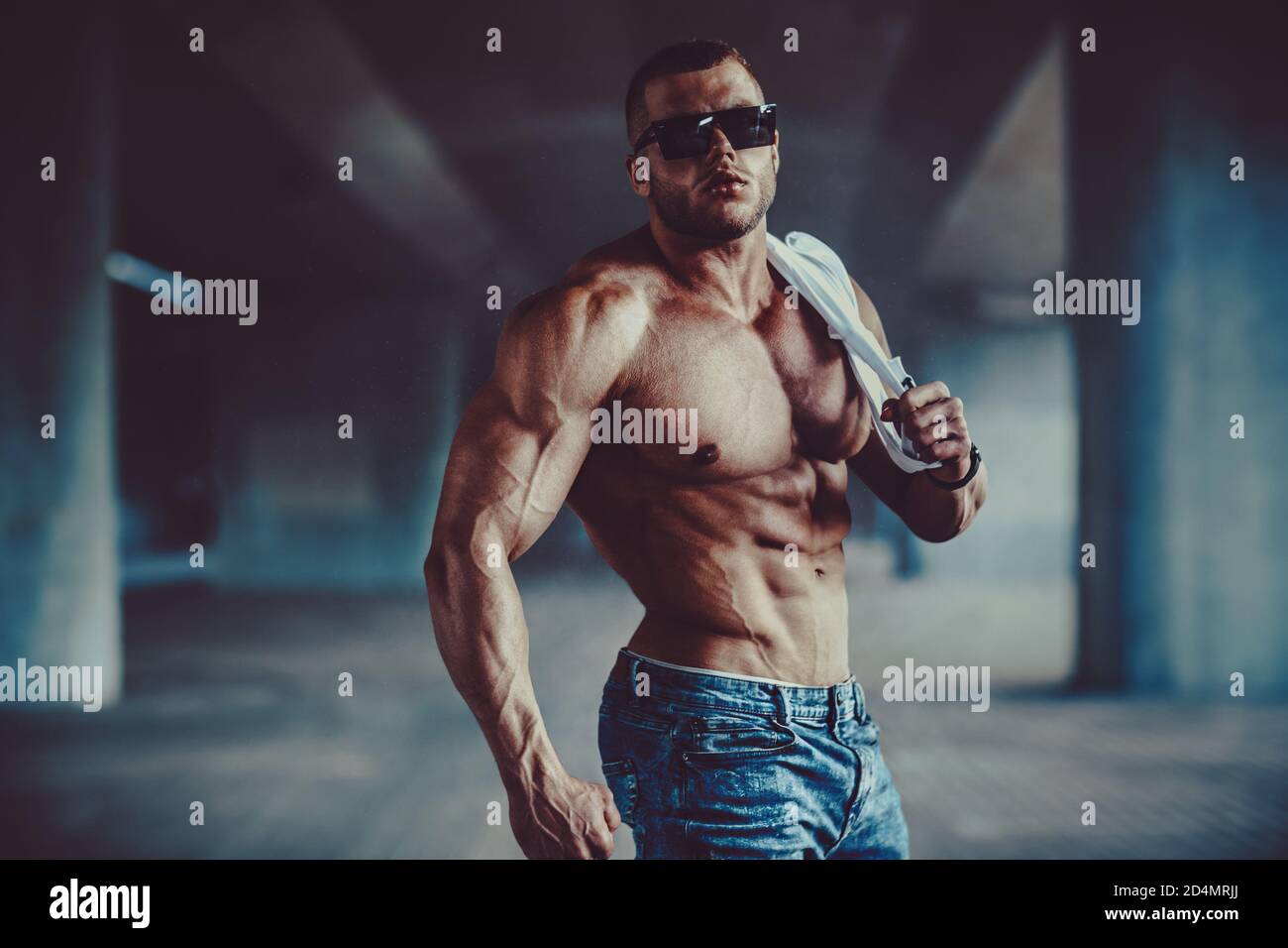 Jeune homme fort bodybuilder avec des lunettes de soleil sur fond urbain Banque D'Images