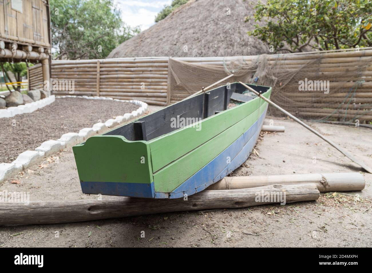 petit bateau en bois vert et bleu avec des verrats, sur quelques poteaux en bois, à côté d'un chemin avec des pierres blanches, détails Banque D'Images