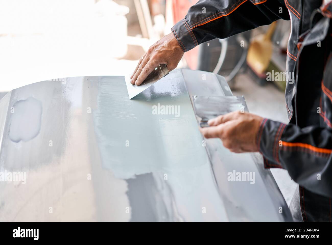 Réparation de la carrosserie, application PuTTY gros plan. Le mécanicien répare la voiture. Travailler après l'accident en travaillant le primaire de ponçage avant de peindre. Banque D'Images