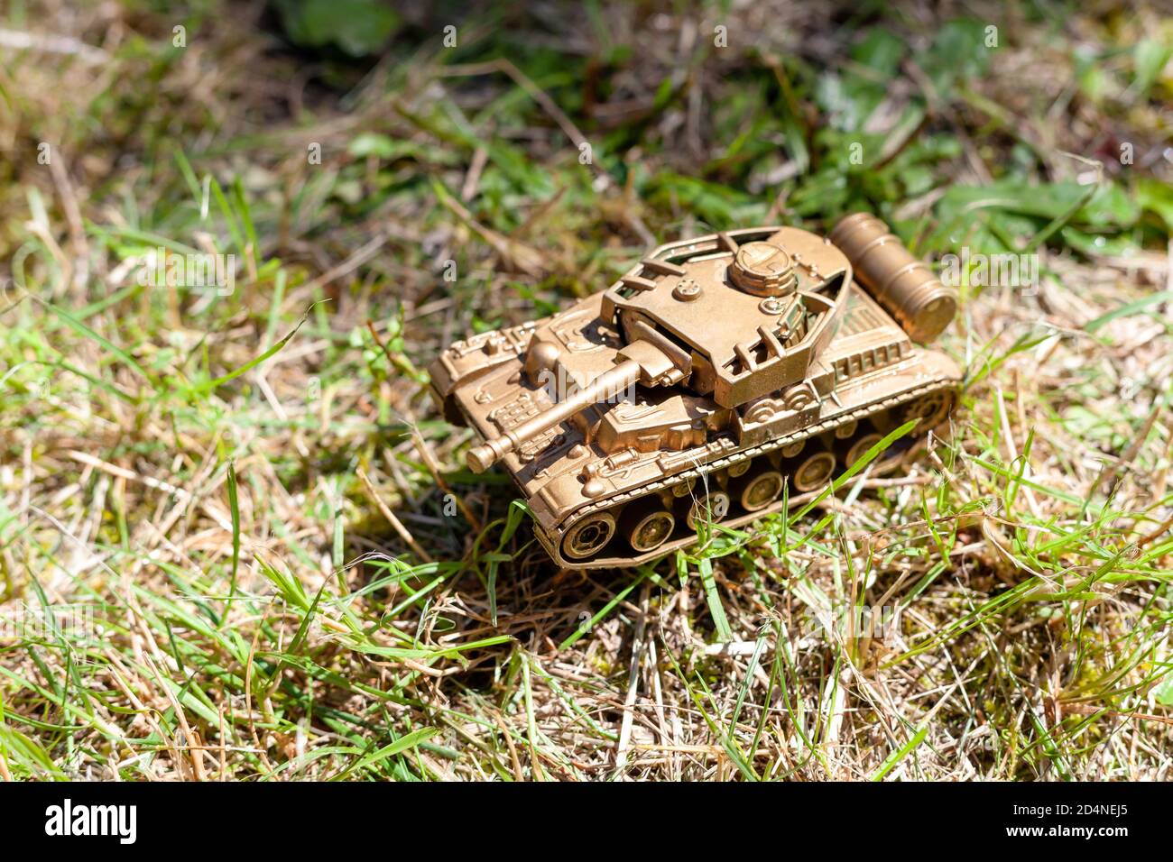 Jouet en plastique réservoir d'or posé sur le sol. Golden tank, véhicule militaire se déplaçant à travers l'herbe des jouets bon marché simples pour les enfants, guerre, zone de guerre Banque D'Images