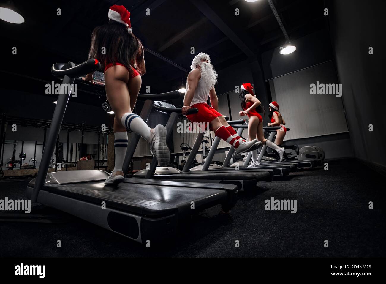 Le Père Noël avec des filles dans les chapeaux du Père Noël dans une salle de sport Banque D'Images