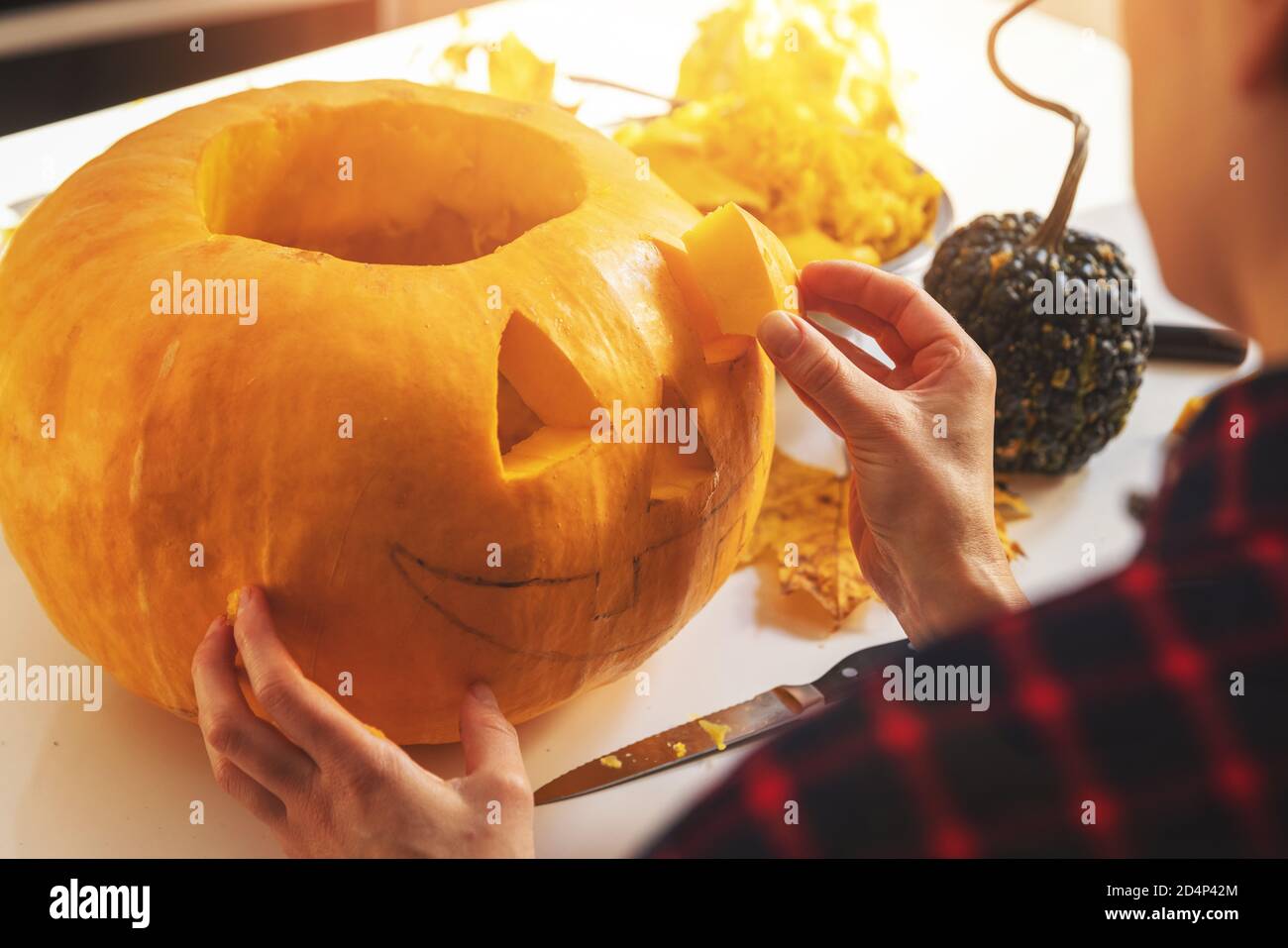 femme sculptant de la citrouille dans une citrouille en forme de citrouille-lanterne pour la décoration des fêtes d'halloween cuisine maison Banque D'Images