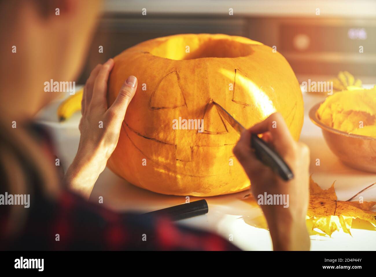 femme sculptant de la citrouille dans une citrouille en forme de citrouille-lanterne pour la décoration des fêtes d'halloween cuisine maison Banque D'Images