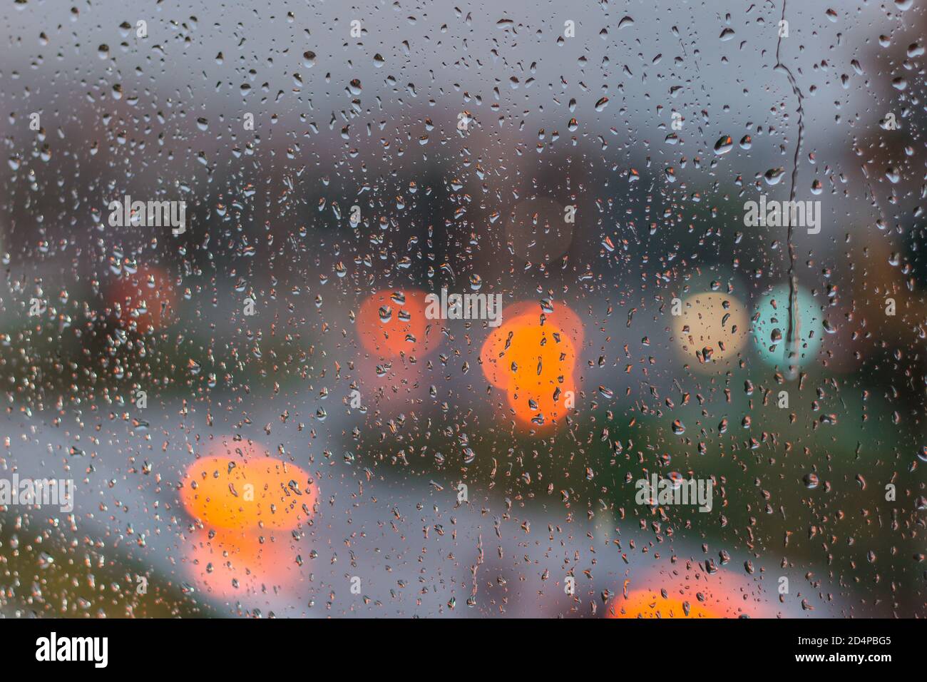 Gouttes sur le verre par jour de pluie. Pluie à l'extérieur de la fenêtre dans la ville. Texture des gouttes de pluie, verre humide. Arrière-plan de fenêtre pluvieuse. Feux de circulation de la ville Banque D'Images