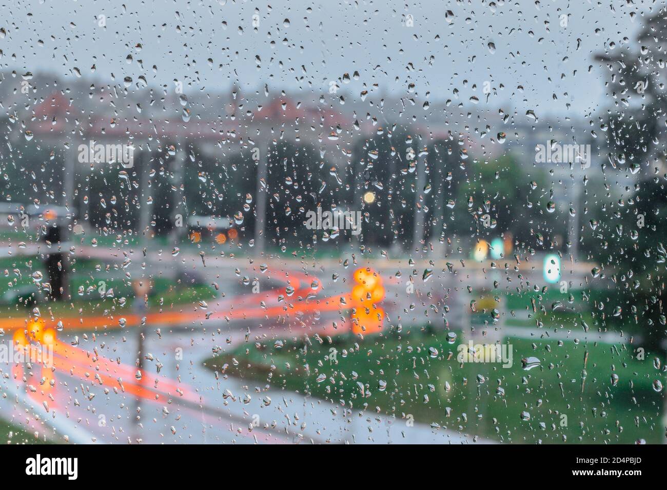 Gouttes sur le verre par jour de pluie. Pluie à l'extérieur de la fenêtre dans la ville. Texture des gouttes de pluie, verre humide. Arrière-plan de fenêtre pluvieuse. Feux de circulation de la ville Banque D'Images