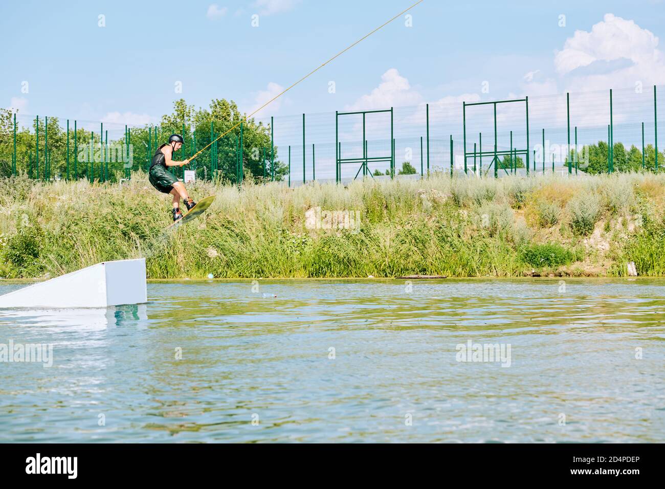 Jeune sportif en casque d'activité et de protection debout sur la planche de surf Banque D'Images