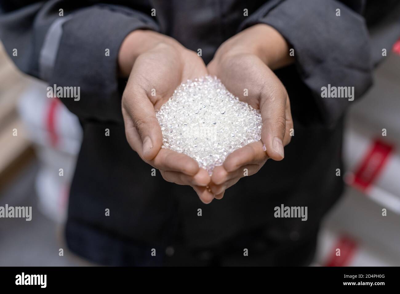 Mains de jeunes ouvriers d'usine tenant pile de blanc non traité granulés de plastique Banque D'Images