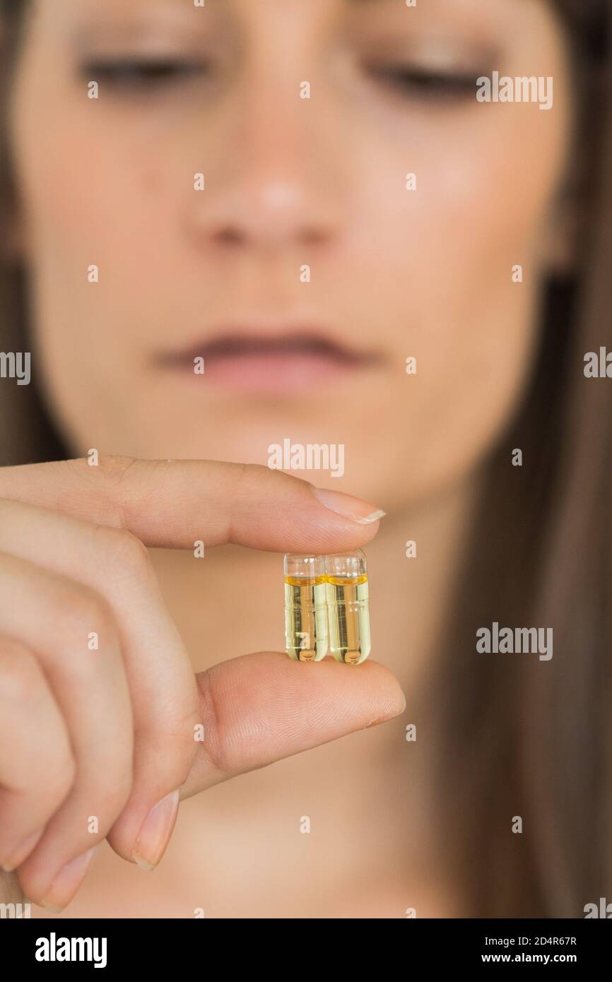 Femme de prendre de l'huile de foie de morue capsules de gélatine. Banque D'Images