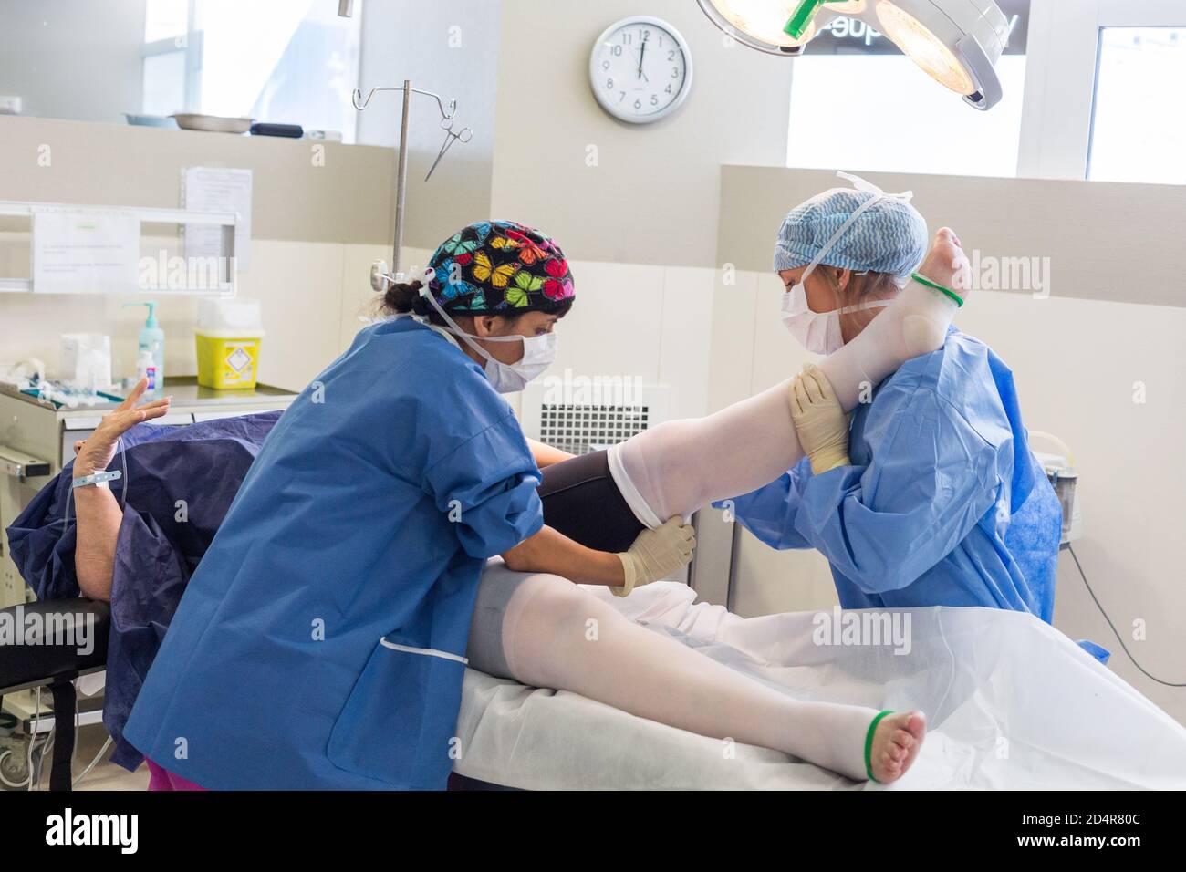 Infirmière qui pose un système de prévention de la thrombose veineuse profonde (TVP) sur les jambes inférieures d'un patient après chirurgie, hôpital privé esthétique d'Aquitaine, Bo Banque D'Images