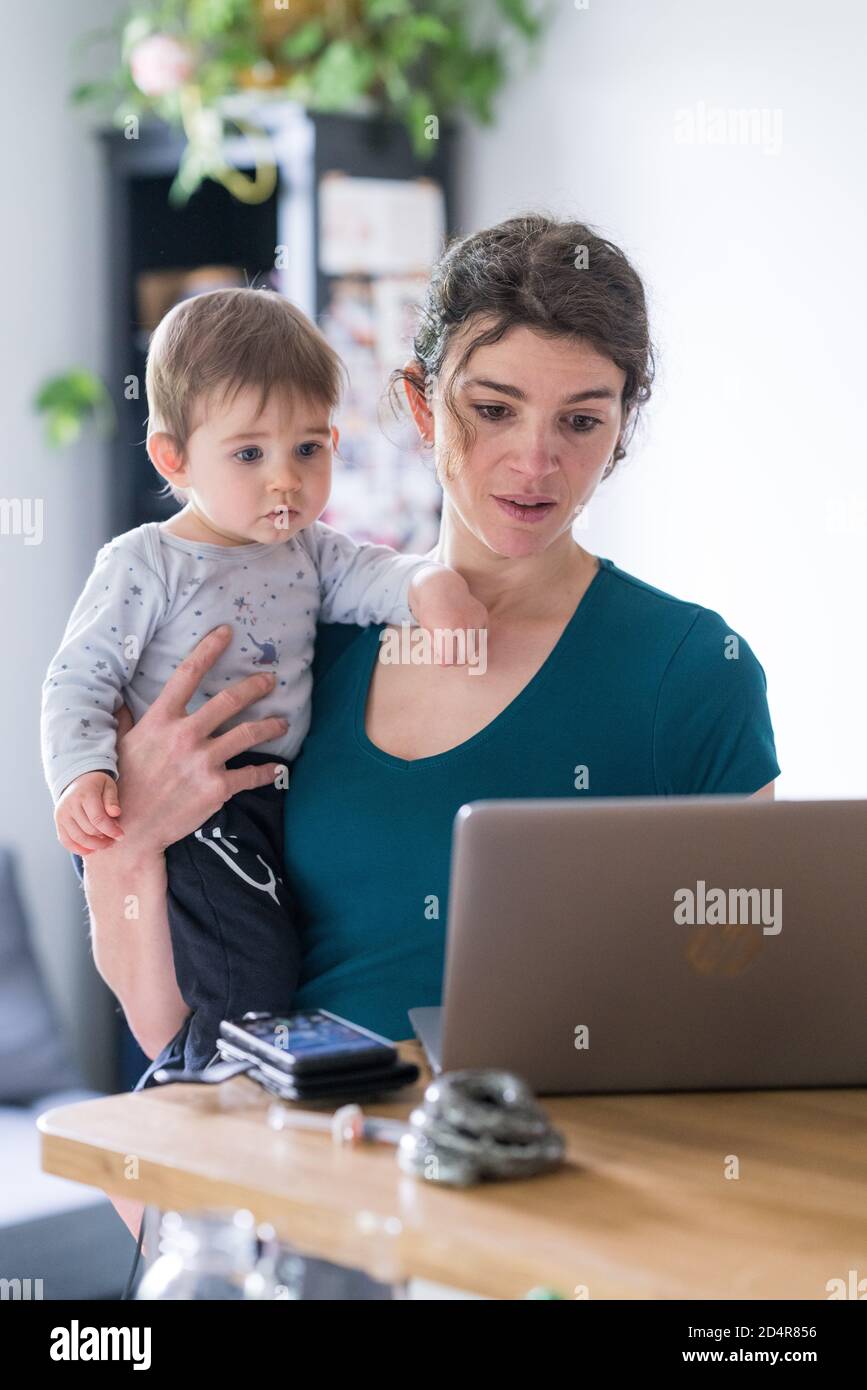 Femme utilisant un ordinateur portable avec son bébé garçon de 9 mois. Banque D'Images
