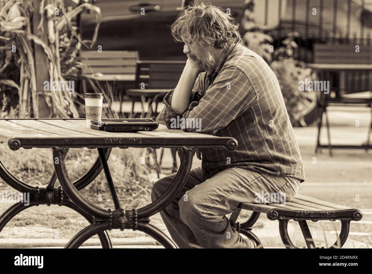 Ellicott City, MD, USA 10/07/2020: Image en noir et blanc d'un vieil homme inconnu assis seul sur un banc de pique-nique, il semble inquiet et réfléchi avec humour Banque D'Images