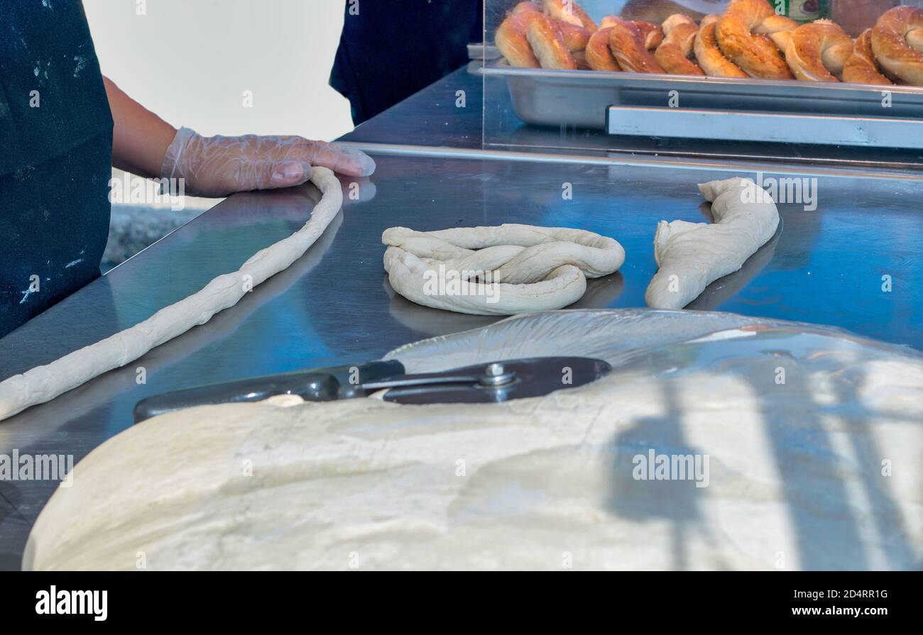 Les rouleaux d'un boulanger pâte crue dans une corde pour faire un bain, des bretzels frais du four Banque D'Images