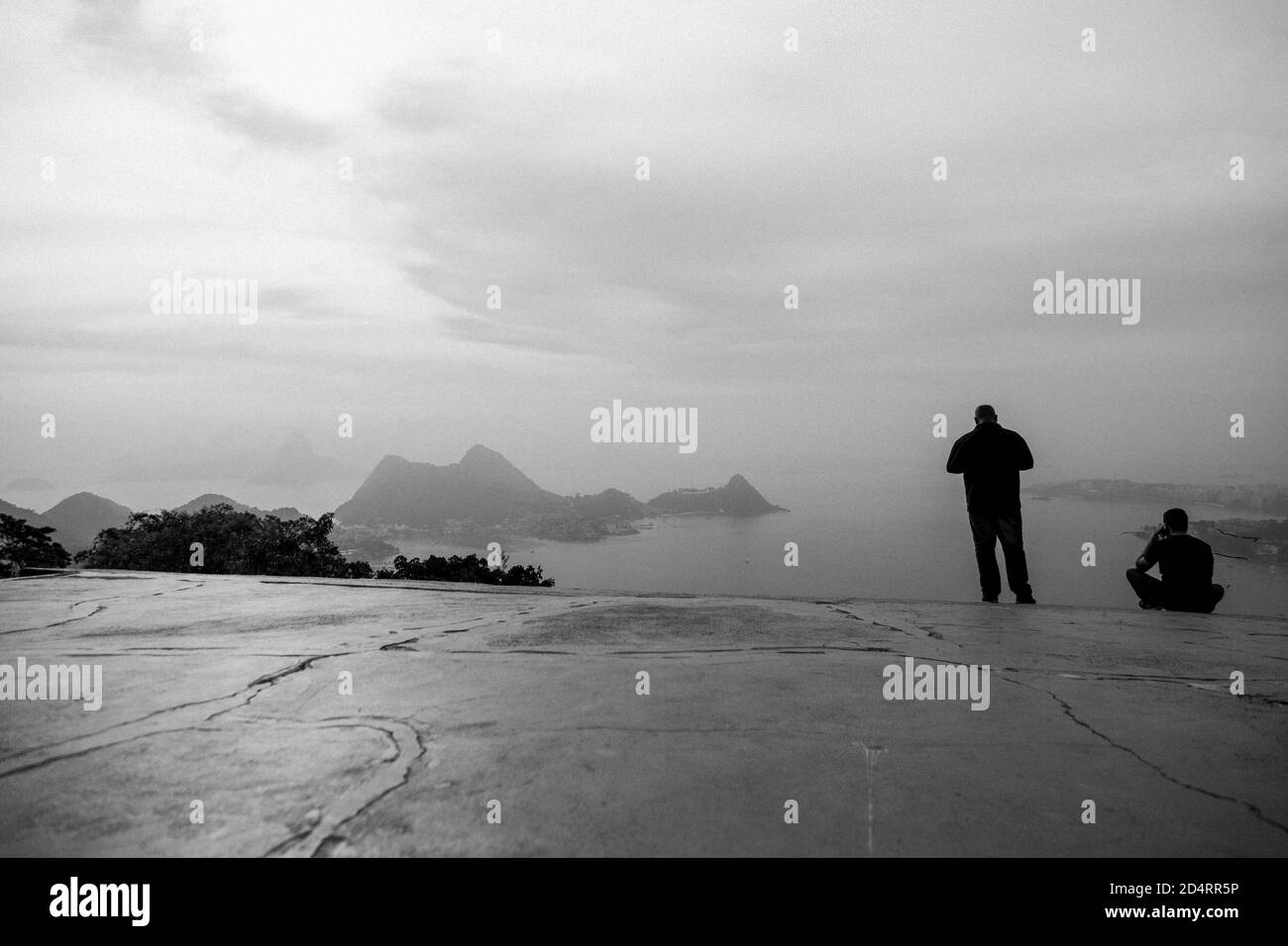 Vue arrière en niveaux de gris des gens qui donnent sur l'océan Banque D'Images