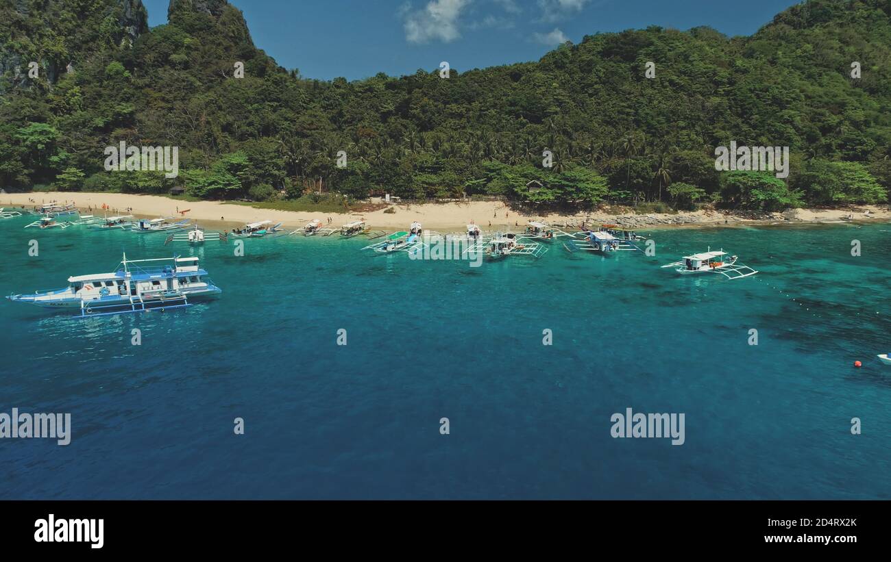 Bateaux sur la baie de l'océan vue aérienne sur la plage de sable. Forêt tropicale de jungle sur l'île de montagne El Nido, Palawan, Philippines. Paysage incroyable avec transport de l'eau au paradis Resort dans une prise de vue cinématographique Banque D'Images