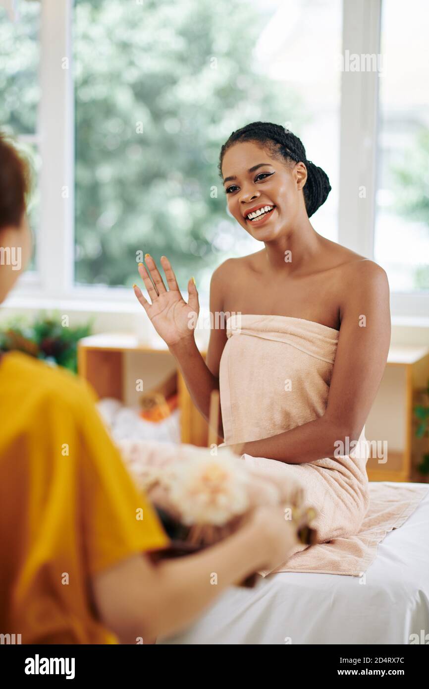 Jolie jeune femme asiatique gaie couverte d'une serviette esthéticienne avec plateau de serviettes Banque D'Images