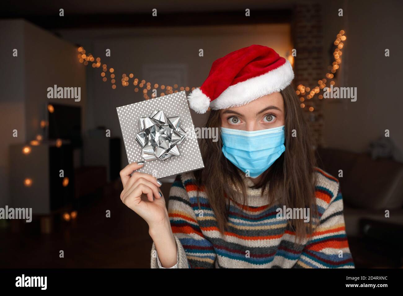 Femme dans le masque montrant le cadeau de Noël Banque D'Images Femme dans le masque montrant le cadeau de Noël Banque D'Images
