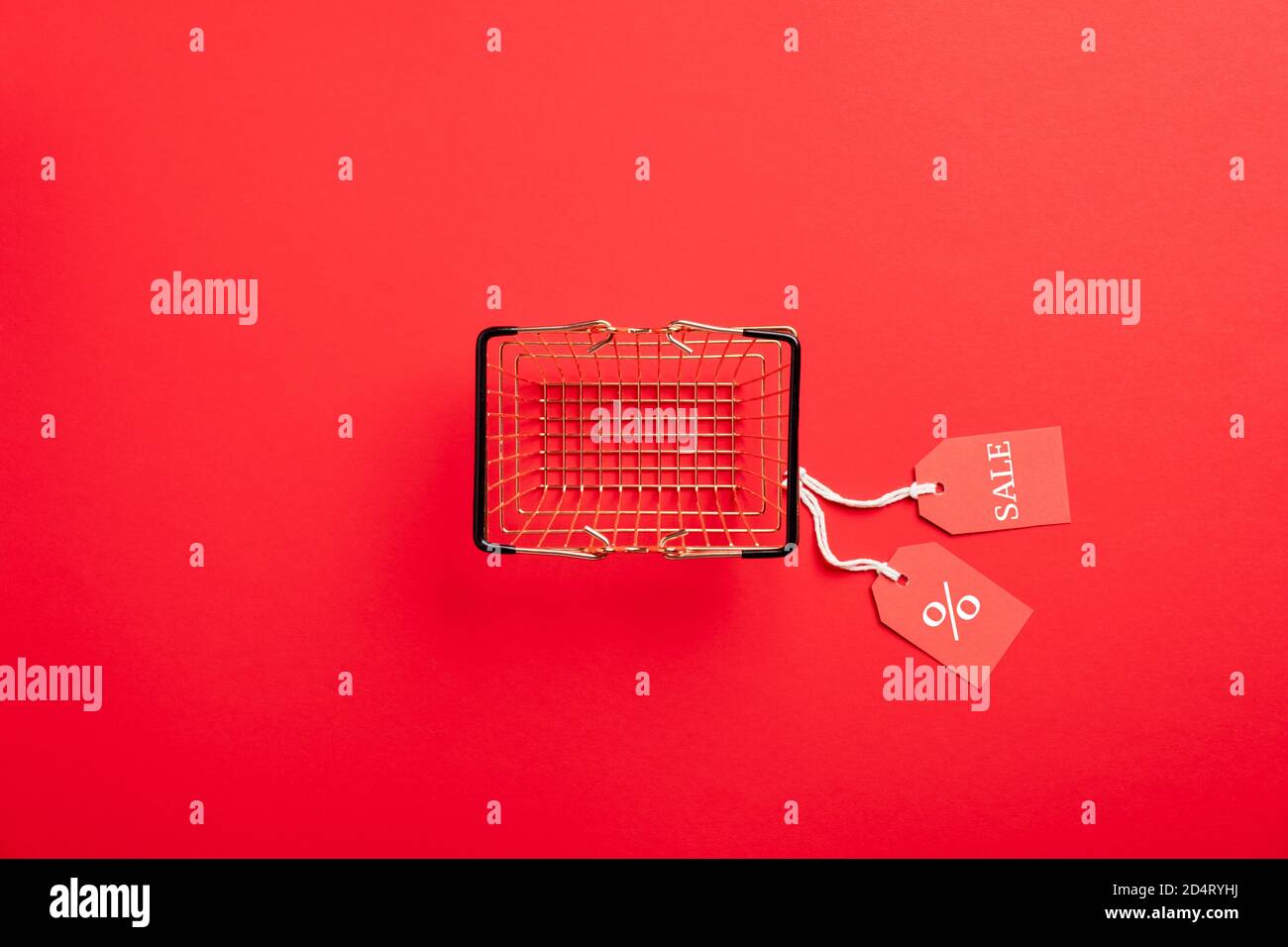 Concept de solde du Vendredi fou. Vider le panier avec les étiquettes de vente sur fond rouge. Flat lay, vue de dessus. Banque D'Images
