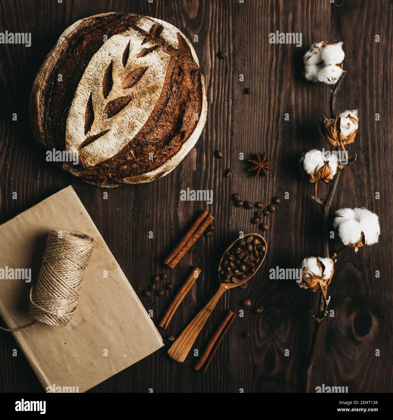 Vue de dessus du pain maison, des grains de café et une branche de laine de coton sur une table en bois. Banque D'Images