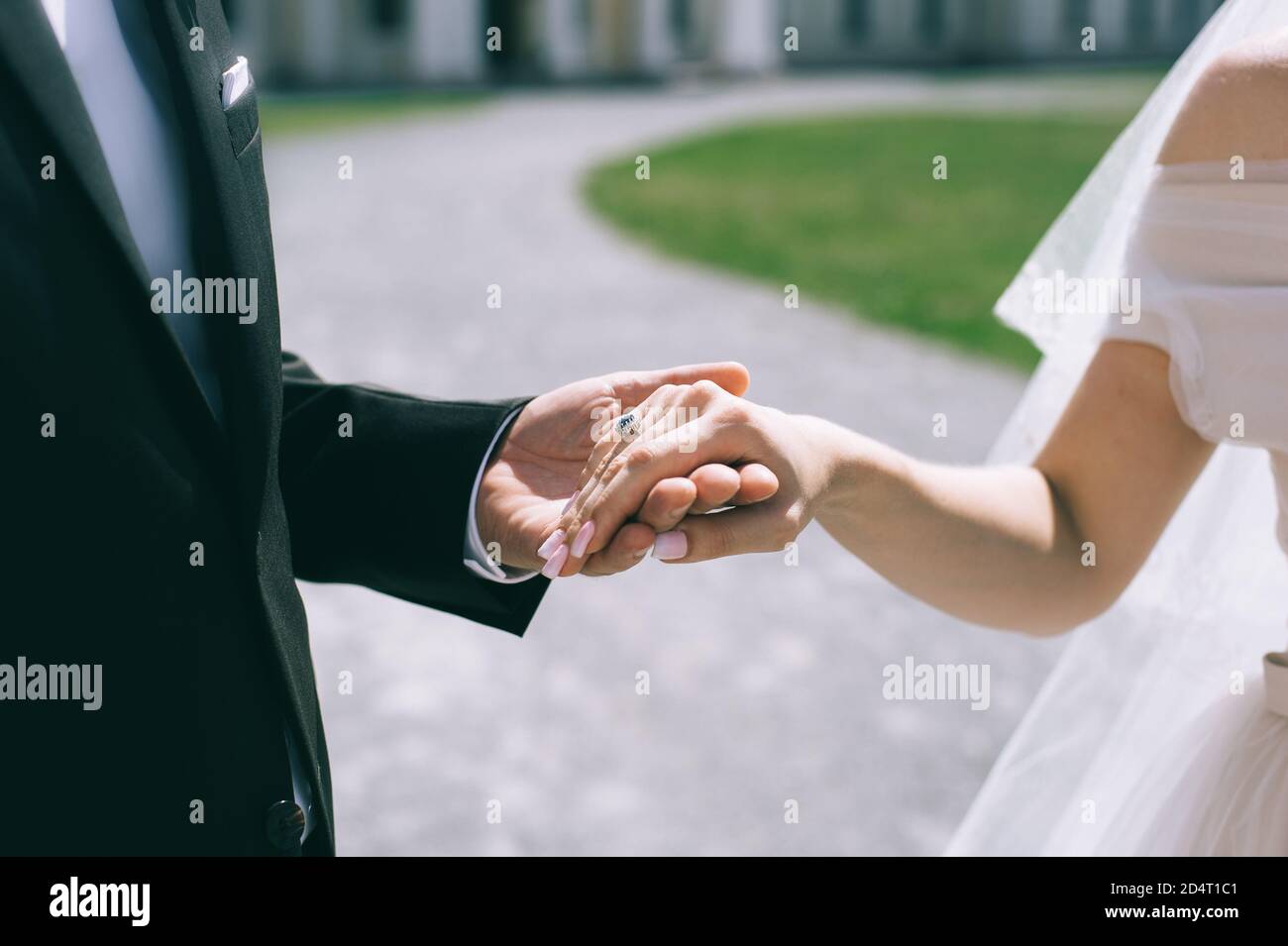 Gros plan d'un couple de mariage tenant les mains à l'extérieur. Arrière-plan flou. Banque D'Images