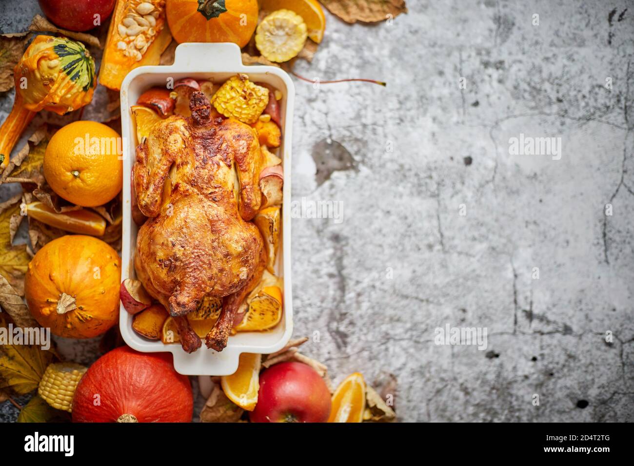 Table de Thanksgiving avec poulet entier rôti ou dinde, citrouille, pommes de terre cuites au four, châtaignes et légumes d'automne grillés. Vue de dessus, au-dessus de la tête. Banque D'Images