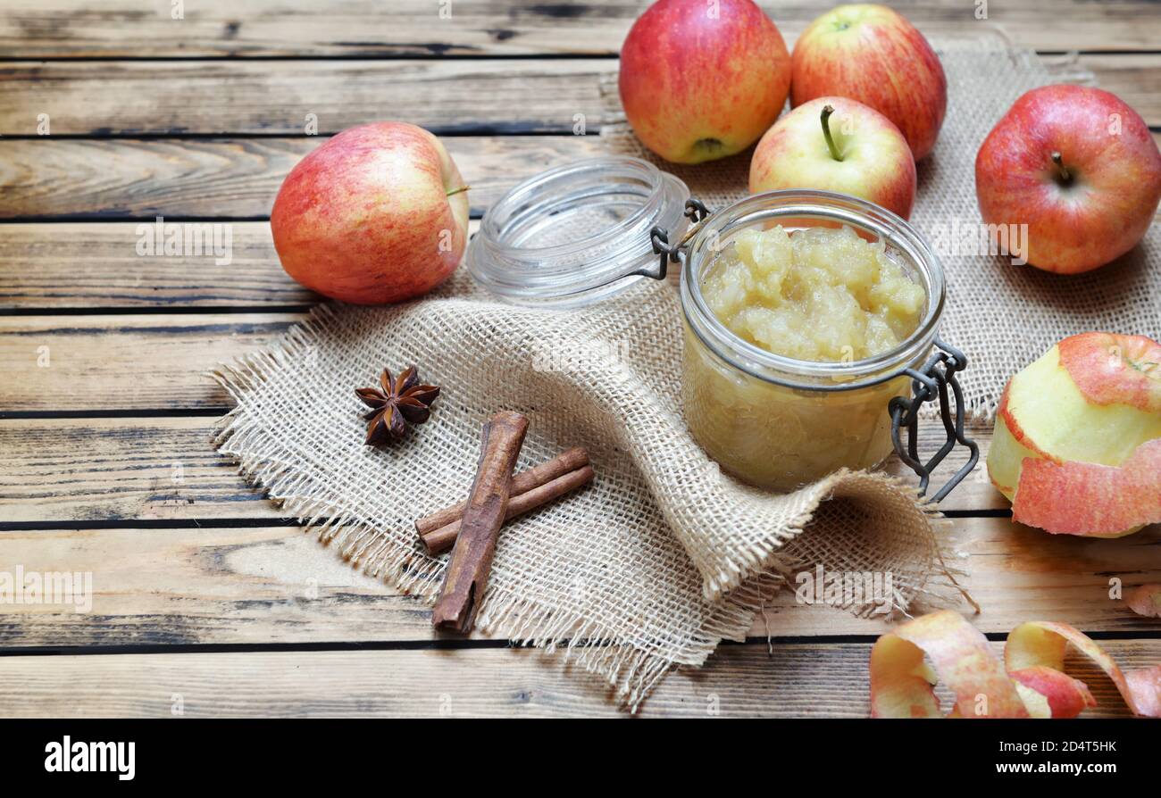 sauce aux pommes maison dans un pot en verre avec des pommes rouges bâton de cannelle sur une table en bois Banque D'Images