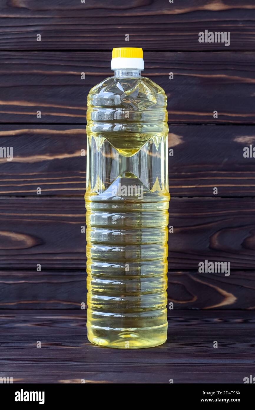 Huile de tournesol dans une bouteille en plastique sur bois foncé, huile à salade jaune, emballage transparent. Produit biologique sain. Ingrédient alimentaire, légume Banque D'Images