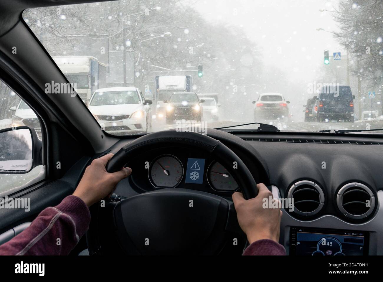 Un homme conduit une voiture sur une ville d'hiver à un blizzard Banque D'Images