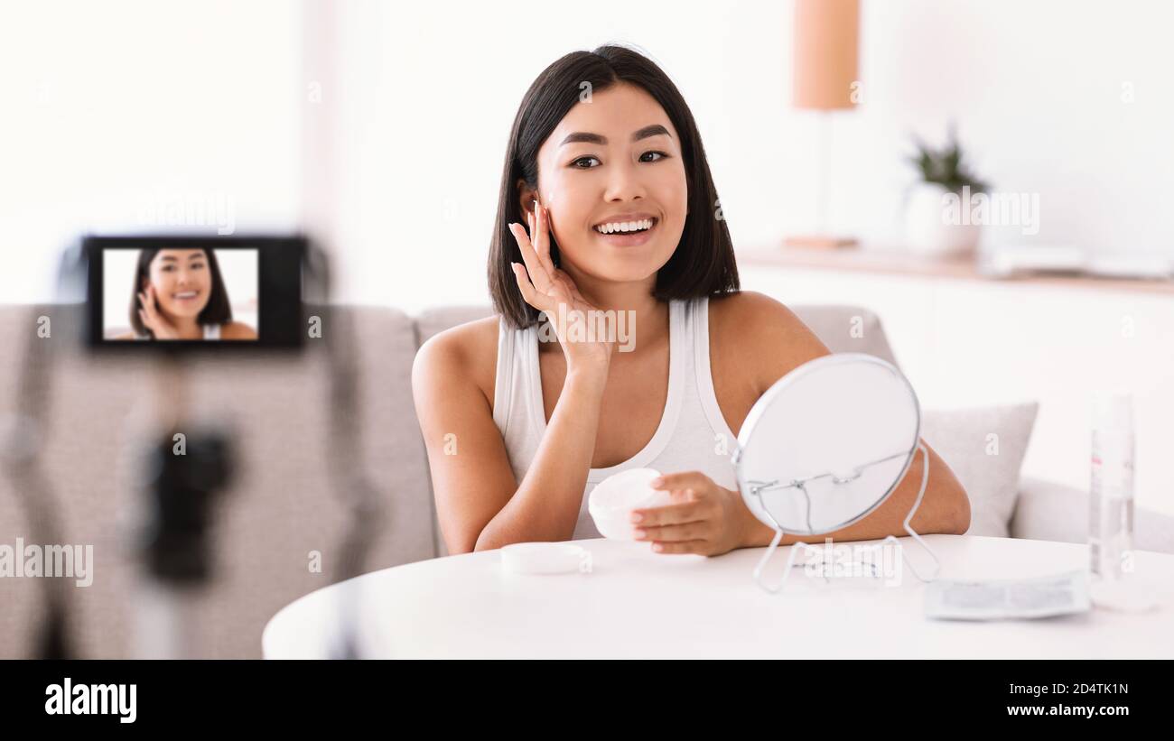 Femme asiatique appliquant de la crème sur son visage pour son vlog Banque D'Images