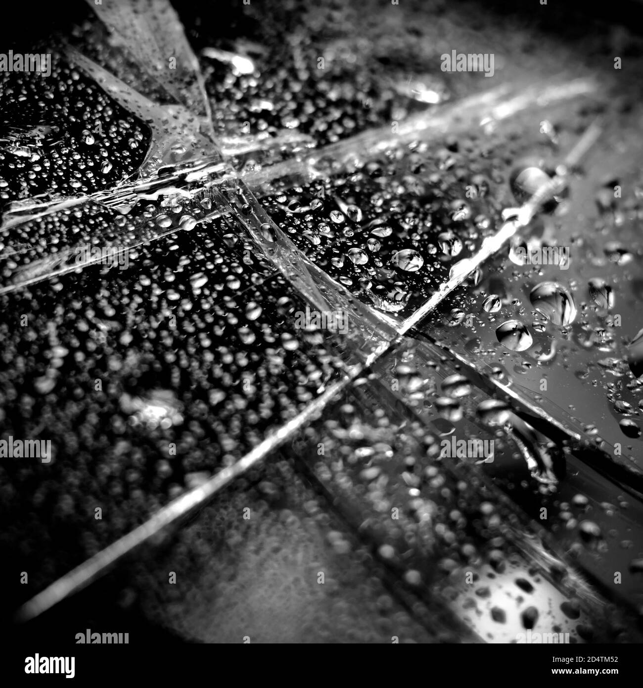 Fond en verre cassé en noir. Arrière-plan minimaliste noir avec fissures sur le verre et gouttes d'eau. Banque D'Images