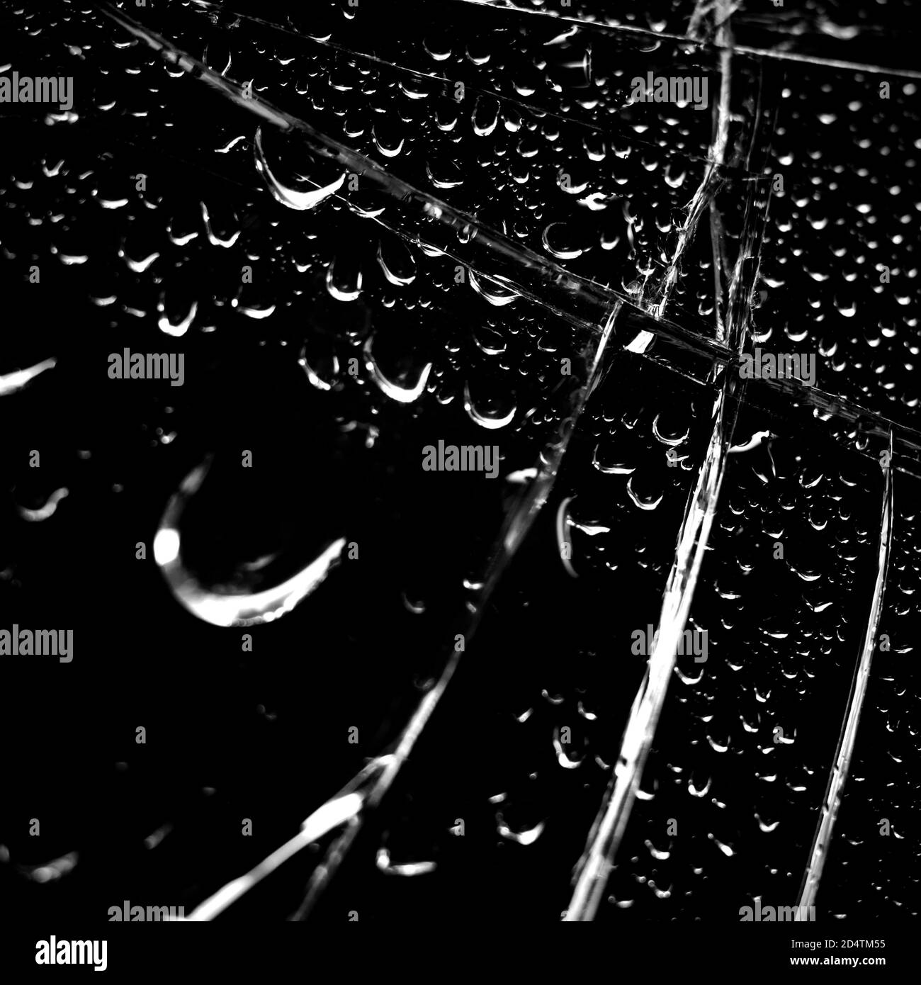 Fond en verre cassé en noir. Arrière-plan minimaliste noir avec fissures sur le verre et gouttes d'eau. Banque D'Images