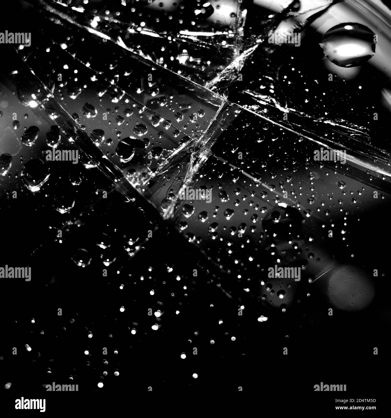 Fond en verre cassé en noir. Arrière-plan minimaliste noir avec fissures sur le verre et gouttes d'eau. Banque D'Images