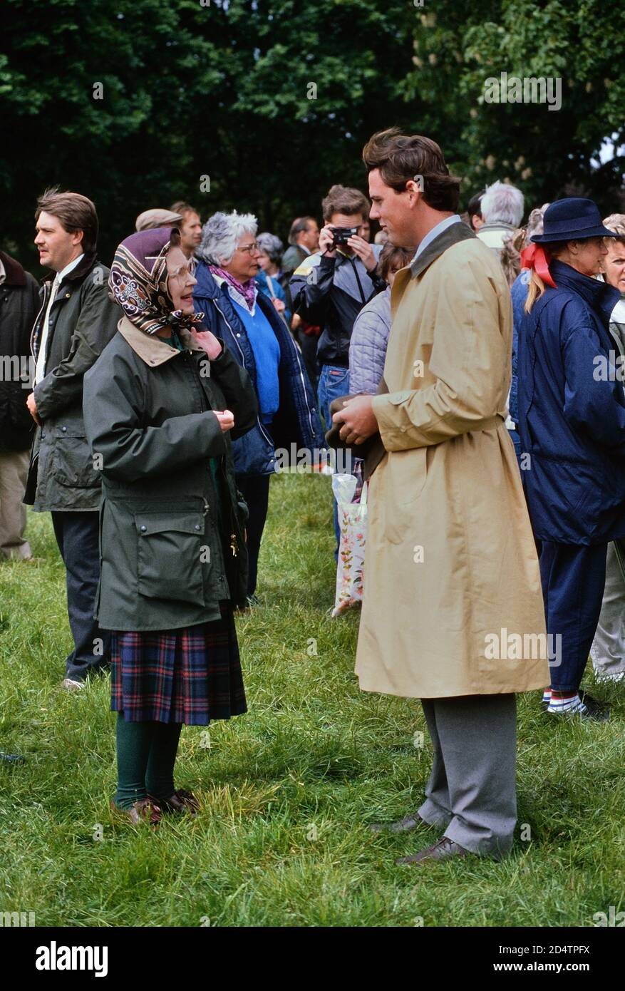 La reine Elizabeth II, portant un foulard, une jupe tartan et une veste cirée verte, en conversation au Royal Windsor Horse Show. 13 mai 1989 Banque D'Images