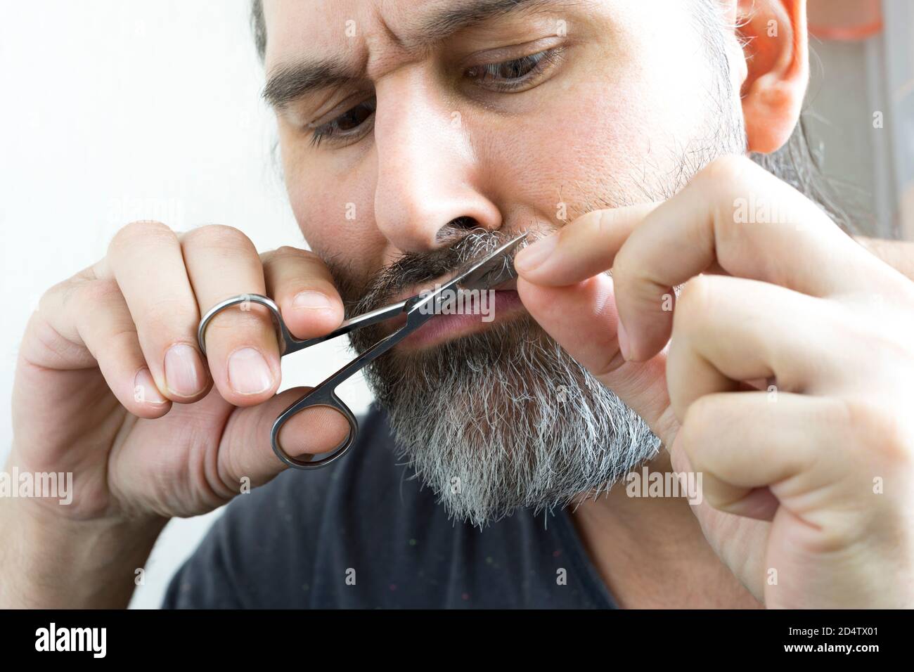 Un barbu coupe soigneusement sa moustache à l'aide d'une petite paire de ciseaux. Vue rapprochée. Banque D'Images