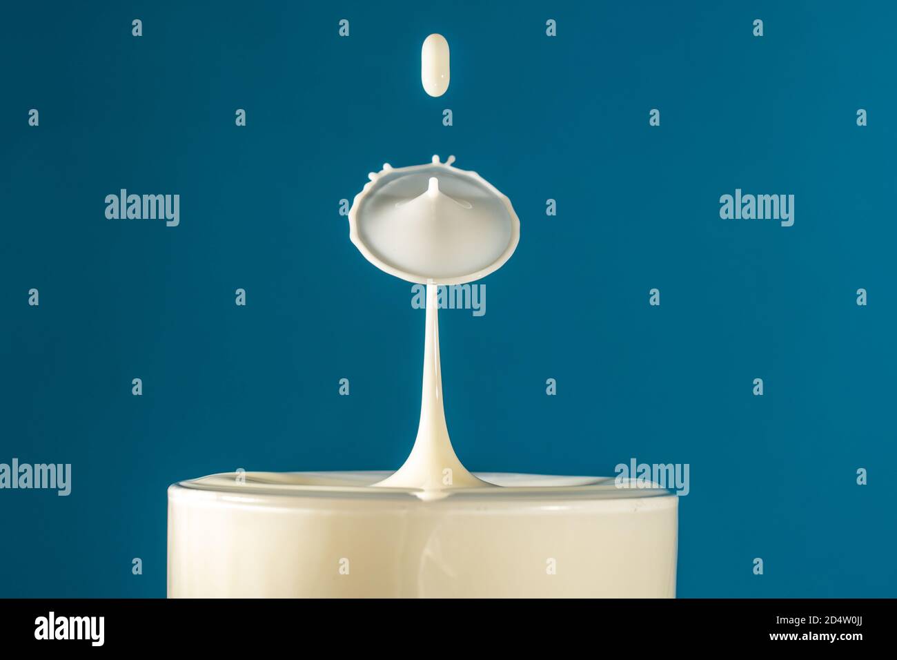 Deux gouttes de lait tombent dans le verre à boisson long se heurtant les uns aux autres, la surface du liquide se forme comme un champignon Banque D'Images