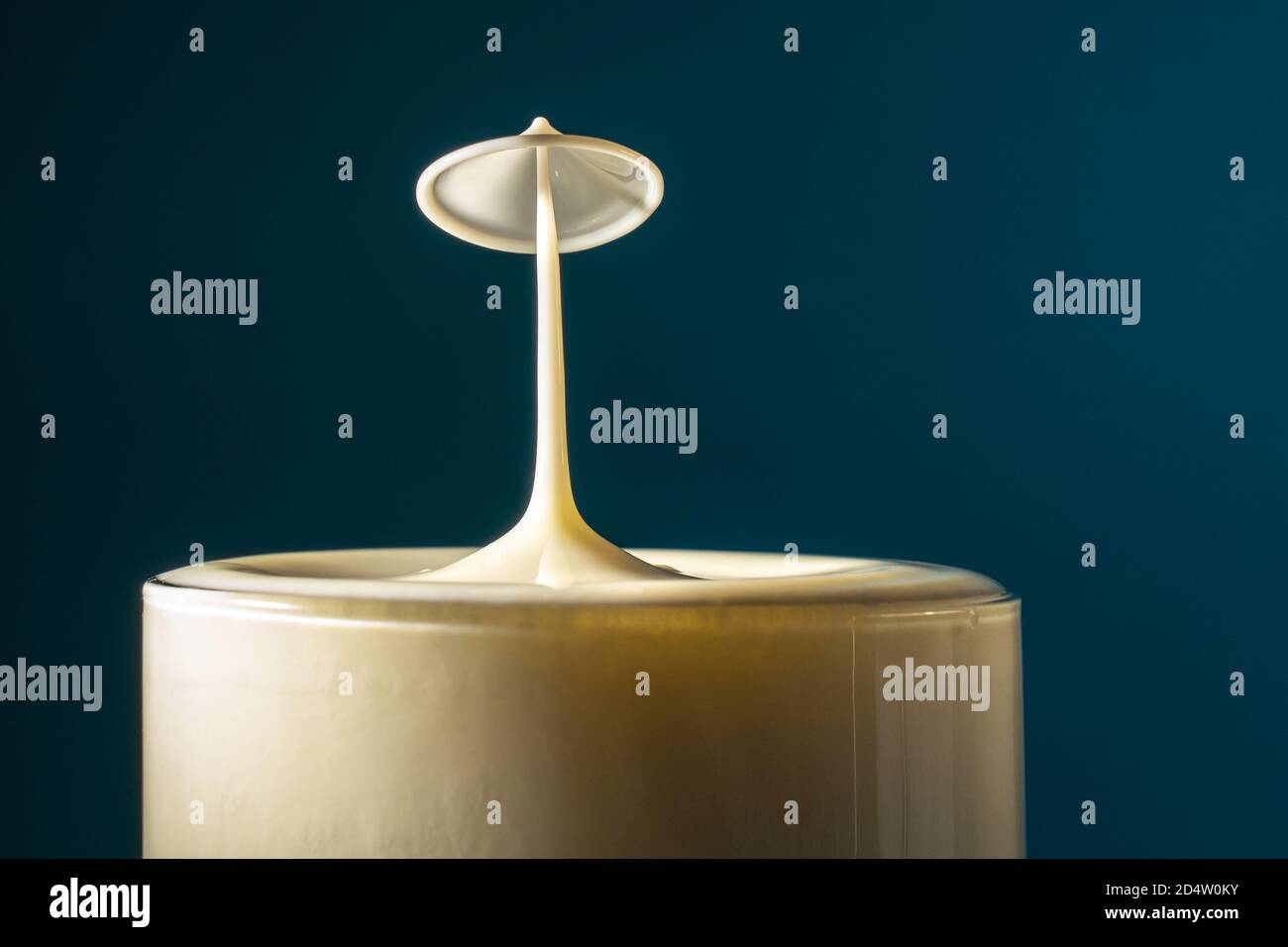 Deux gouttes de lait tombent dans le verre à boisson long se heurtant les uns aux autres, la surface du liquide se forme comme un champignon Banque D'Images