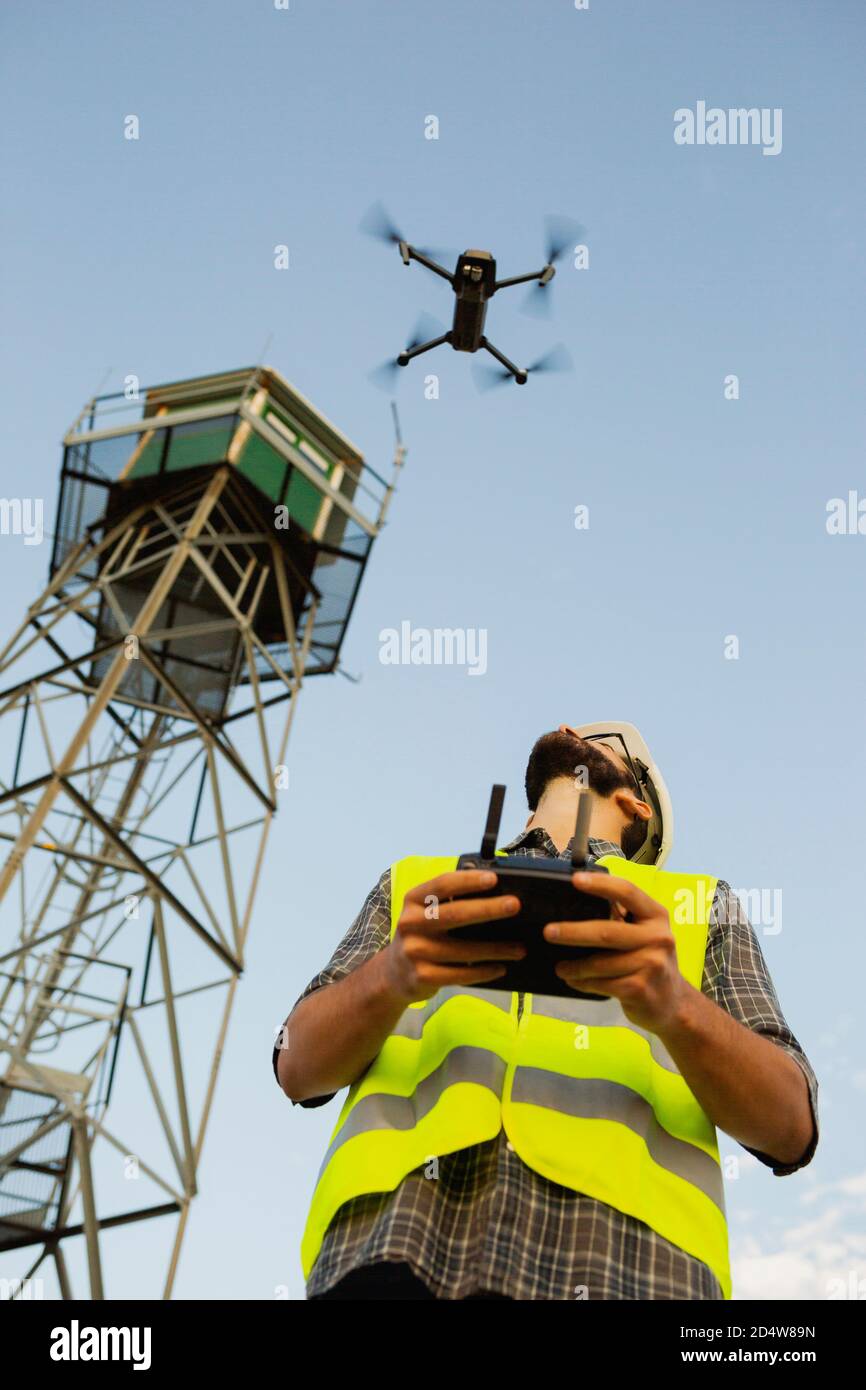 Opérateur de drone homme pilotant un drone à côté d'une tour Banque D'Images