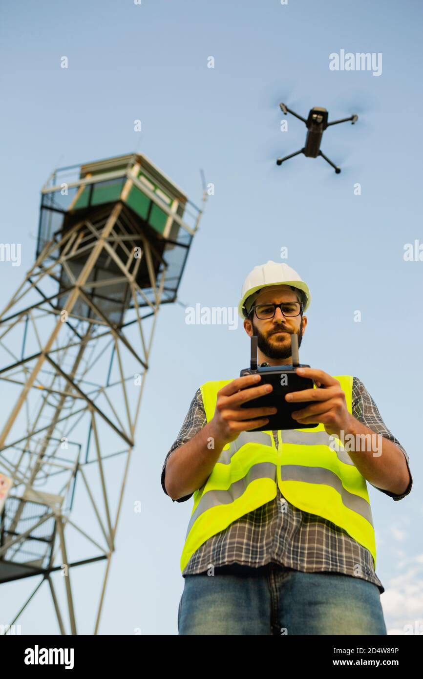 Opérateur de drone homme pilotant un drone à côté d'une tour Banque D'Images