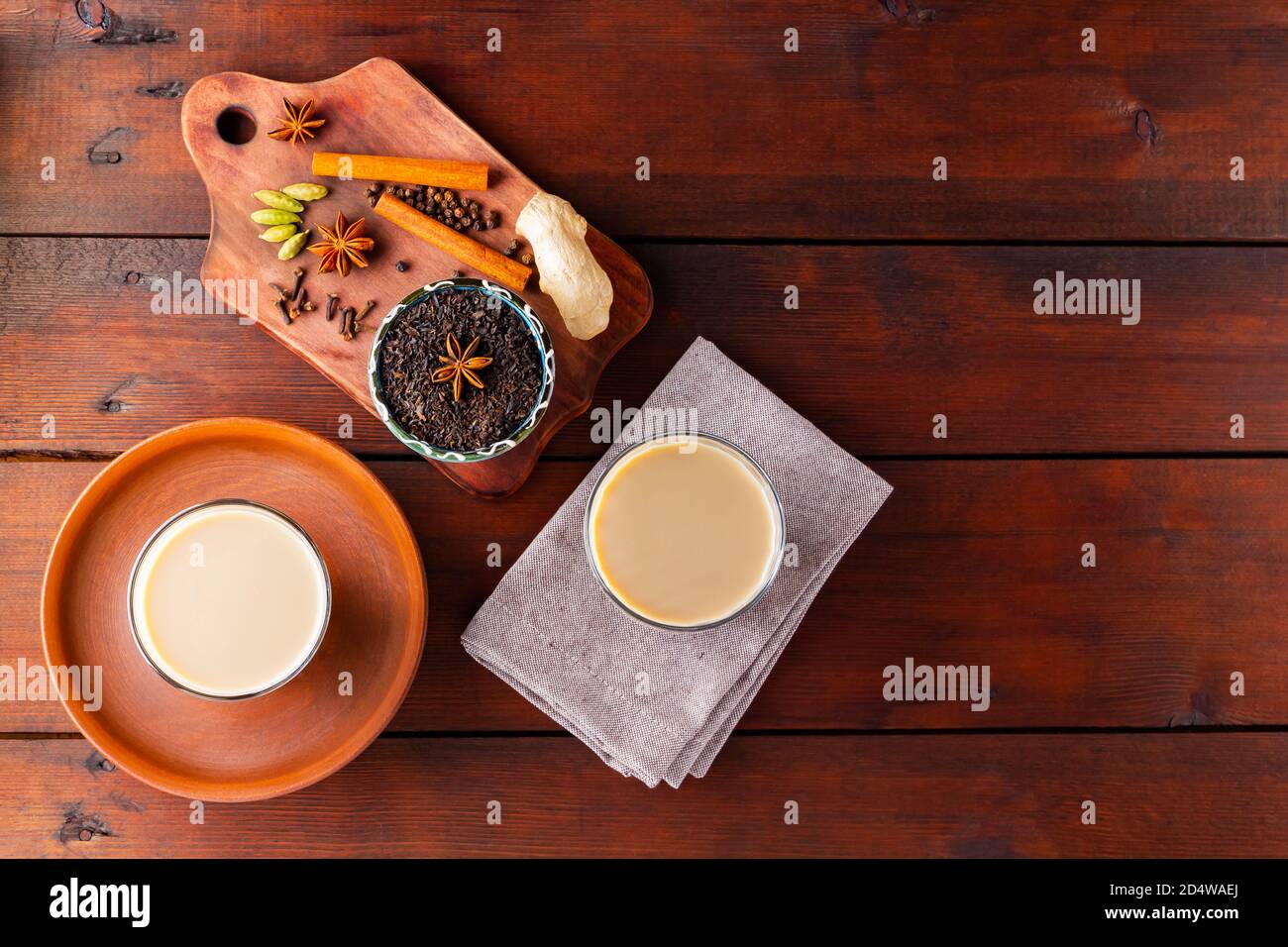Deux verres de thé masala et divers ingrédients. Thé Chai au masala sur des planches en bois. Thé au lait et épices. Copier l'espace. Vue de dessus Banque D'Images