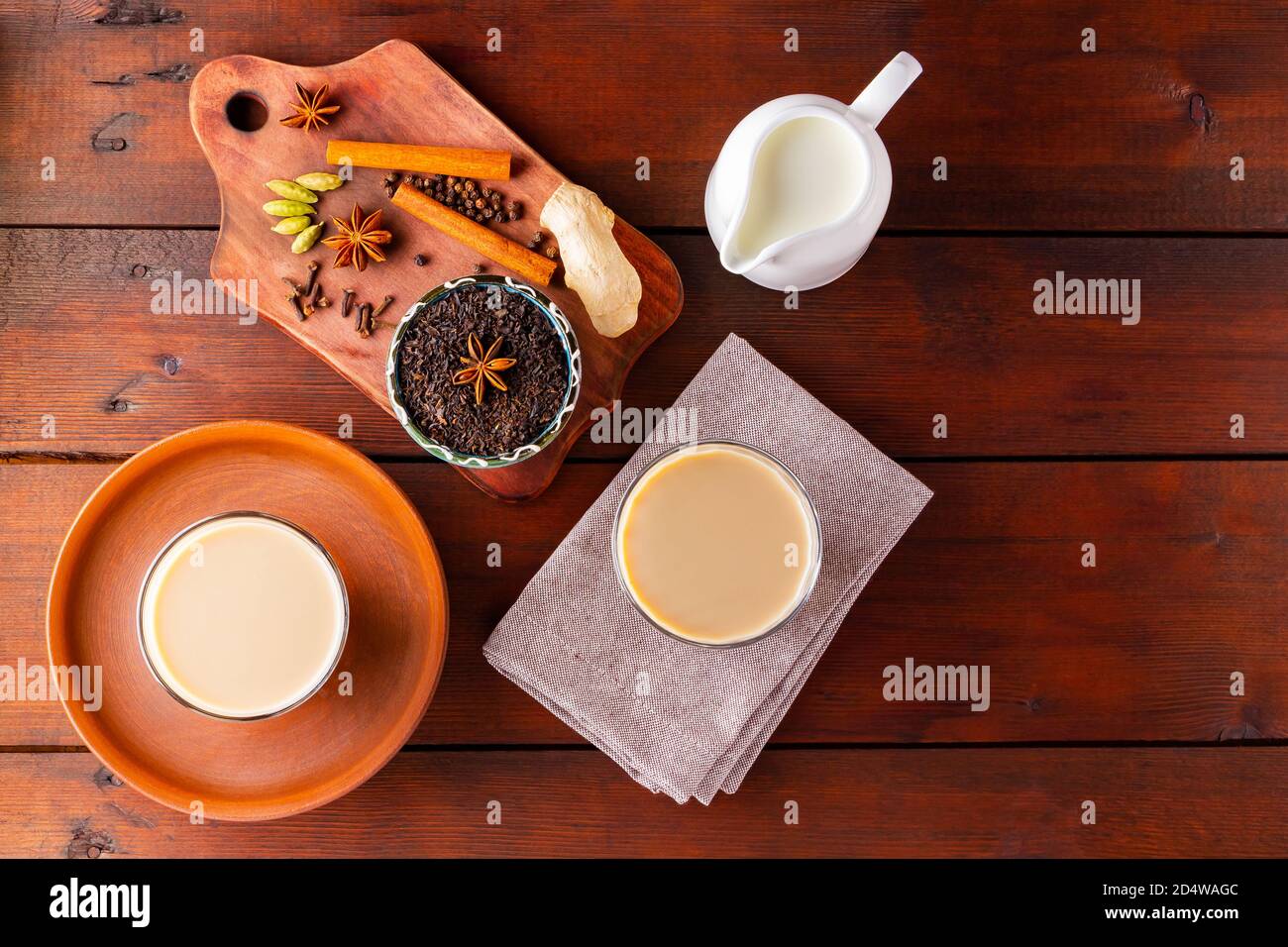 Deux verres de thé masala et divers ingrédients. Thé Chai au masala sur des planches en bois. Thé au lait et épices. Copier l'espace. Vue de dessus Banque D'Images