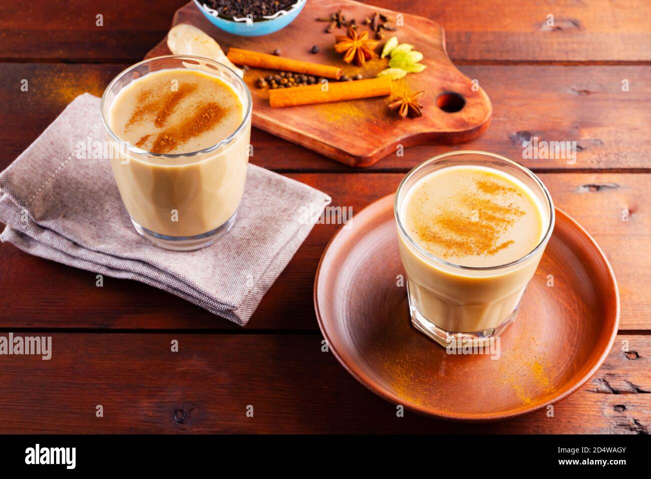 Deux verres de thé masala et divers ingrédients. Thé Chai au masala sur des planches en bois. Thé au lait et épices. Copier l'espace. Vue de dessus Banque D'Images