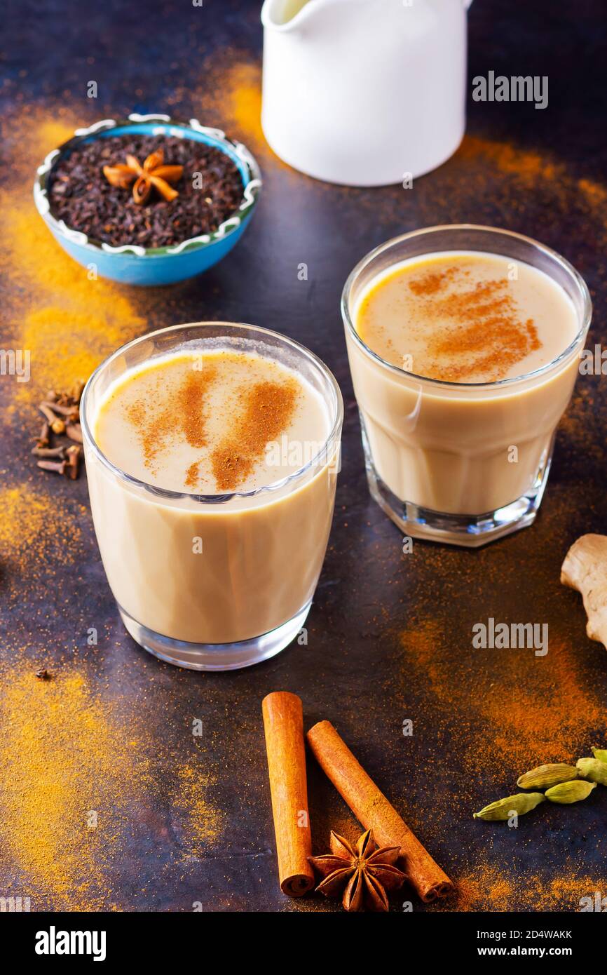 Masala chai thé et pot à lait sur fond noir. Deux verres de thé masala et épices éparses. Vue de dessus Banque D'Images