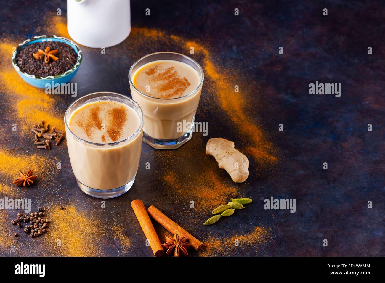 Masala chai thé et pot à lait sur fond noir. Deux verres de thé masala et épices éparses. Vue de dessus Banque D'Images